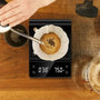 Du café est versé dans une tasse sur une balance digitale qui pèse en direct