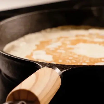 Une crêpe cuit dans une poêle en fonte 