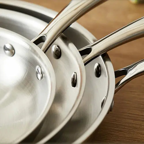 Trois poêles inox empilées vu de prêt