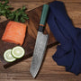 Couteau en acier damas et manche tricolore sur une planche en bois à côté d'un morceau de poisson