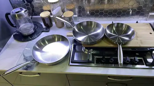 3 poêles en acier inoxydable sûr les fourneaux d'une cuisine moderne sous couleur froide et claire