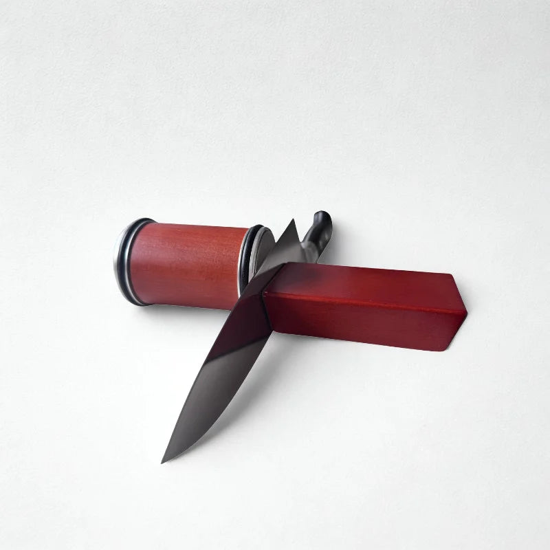 Aiguiseur rotatif en bois et couteau sur fond blanc