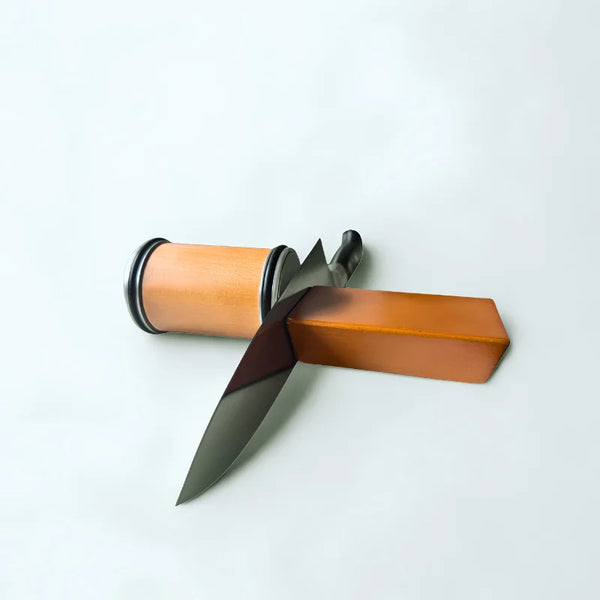 Aiguiseur rotatif en bois et couteau sur fond blanc