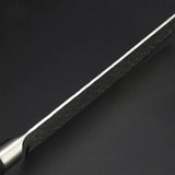Vue du dos de la lame d'un couteau nakiri sur fond gris