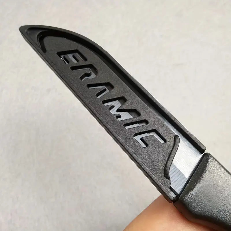 Couteau céramique noir et étui tenu par une main sur fond blanc