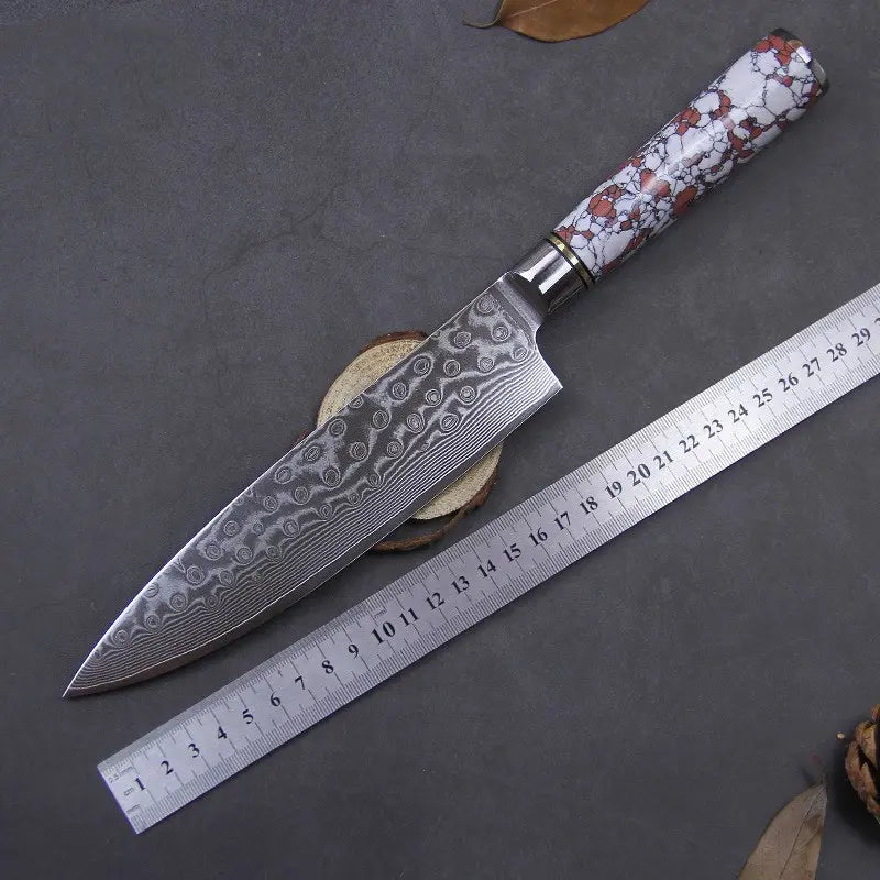 Couteau de chef en acier damas manche rouge et blanc et outil de mesure sur fond gris