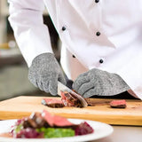 Mains avec gants anti-coupûtres coupent un steak