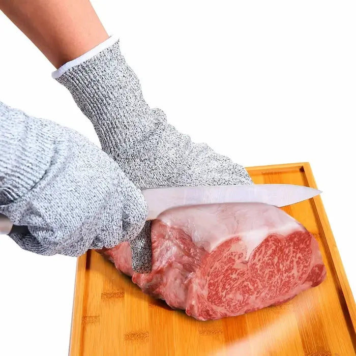 Mains avec gants anti-coupûtres coupent côte de bœuf 