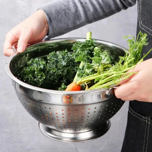 Passoire en Inox remplie de légumes tenues par 2 mains