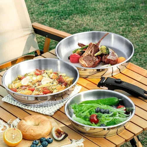 Set de 3 poêles en inox amovibles sur une table en bois dans un jardin