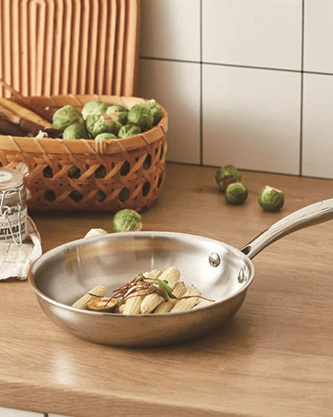 Légumes, panier et poêle inox sur support bois