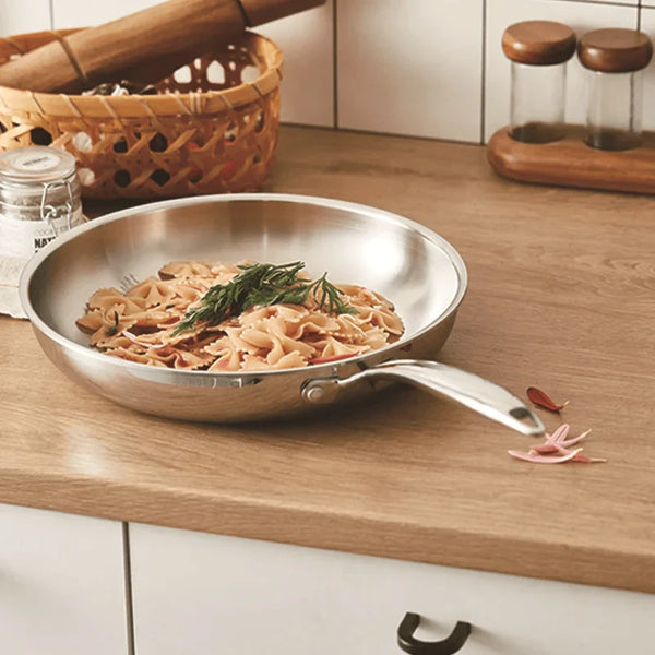 Pâtes dans poêle inox sur support bois