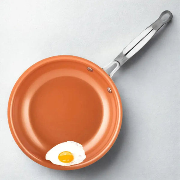 Poêle orange et œuf sur fond blanc