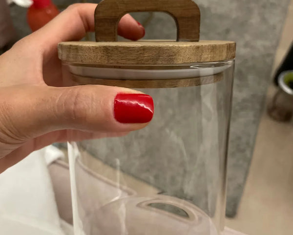 Pot hermétique en verre avec couvercle en bois, tenu par une main