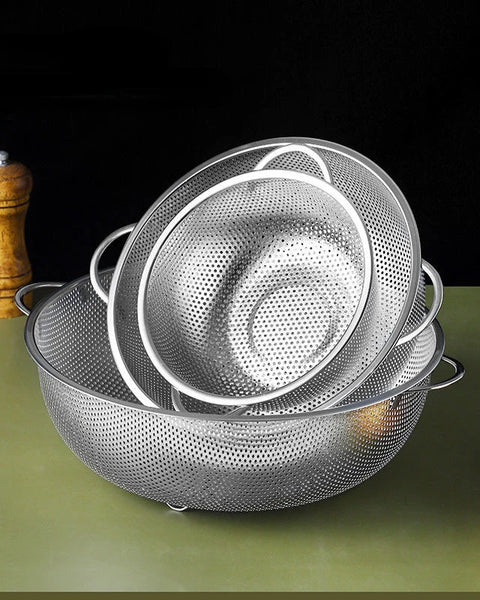 Trois passoires en inox sur un support vert