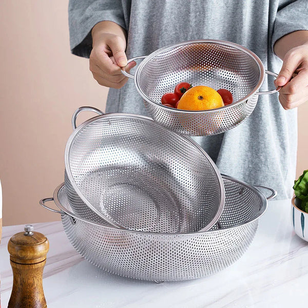 Trois passoires en inox, dont deux sûr une table et une entre deux mains