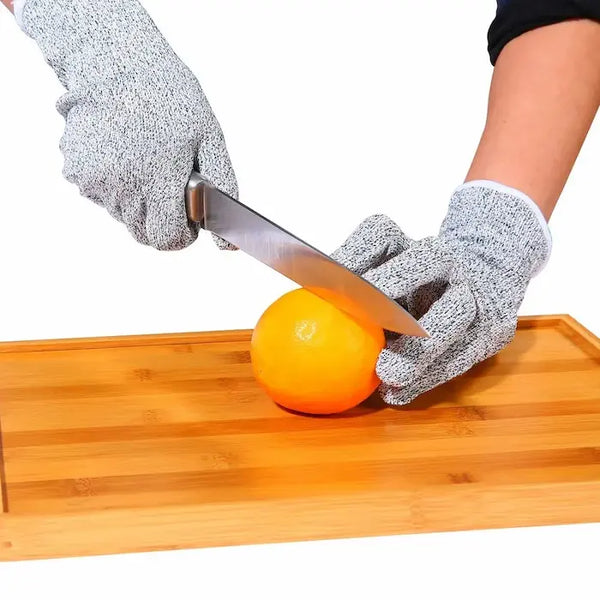 Mains avec gants anti-coupûtres coupent une orange