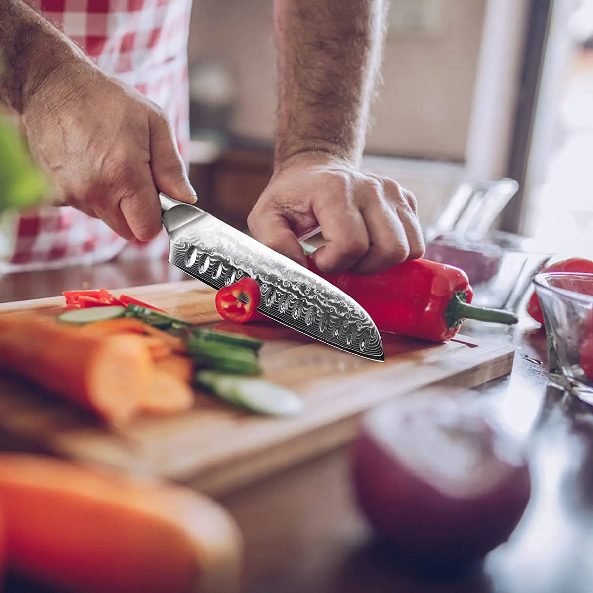 Couteau santoku en acier damas en action.