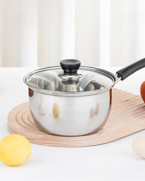 Casserole en inox à un manche sur une planche en bois.