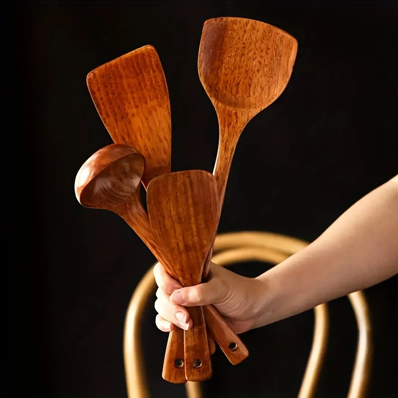 Ustensiles de Cuisine en Bois tenus dans une main sûr fond noir