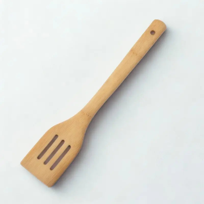 Spatule à trous en bambou sur fond blanc