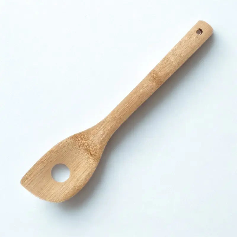 Spatule à trou en bambou sur fond blanc