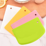 Coupe-pâtes en silicone rose, jaune, vert et blanc sur fond blanc et bois