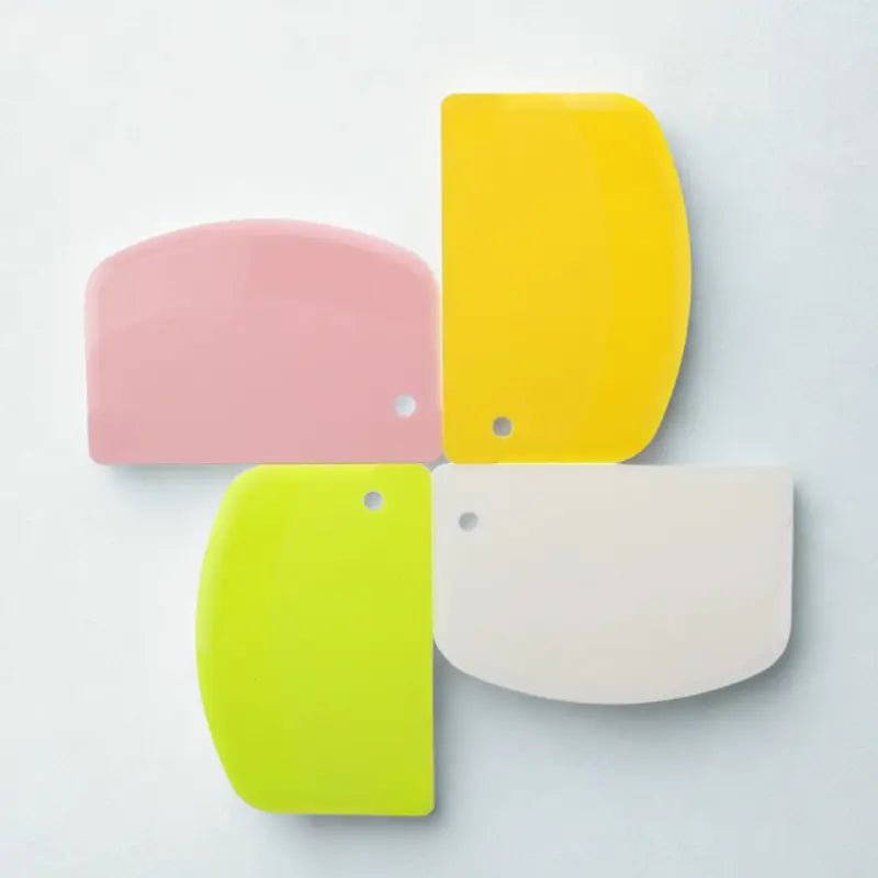 Coupe-pâtes en silicone rose, jaune, vert et blanc sur fond blanc