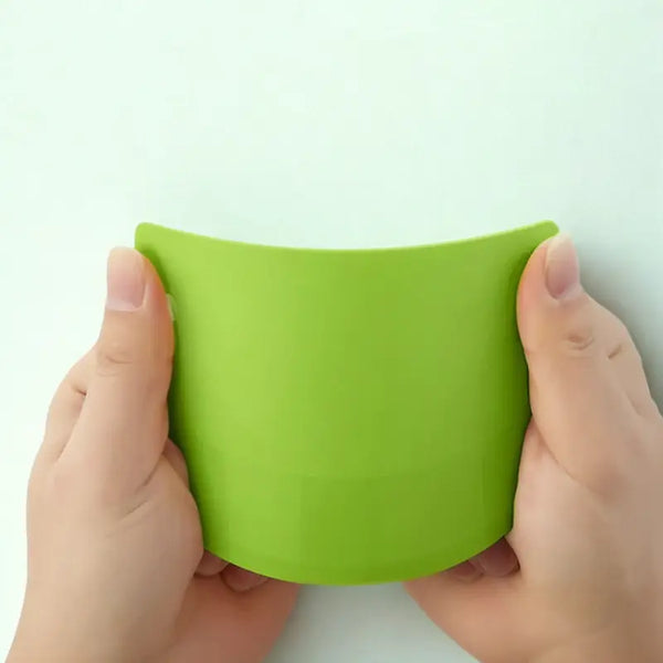 Coupe-pâte en silicone vert tenu par des mains sur fond blanc