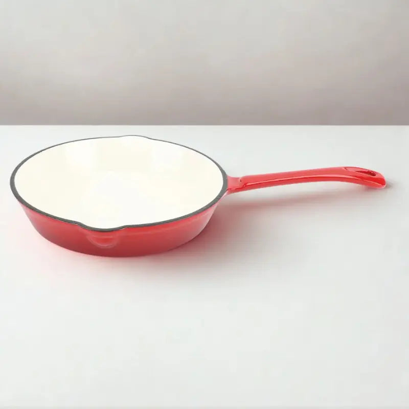 Poêle en Fonte émaillée rouge et blanche sur fond blanc vue de la tranche